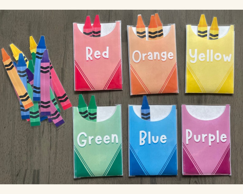 May include: Six colorful envelopes with the words "Red", "Orange", "Yellow", "Green", "Blue", and "Purple" printed on them. Each envelope has two crayon-shaped cutouts with the corresponding color.
