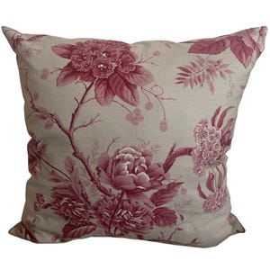 May include: Square decorative pillow with a floral pattern. The pillow features a light beige background with a repeating pattern of burgundy-colored flowers and foliage. The flowers include peonies and other blooms.