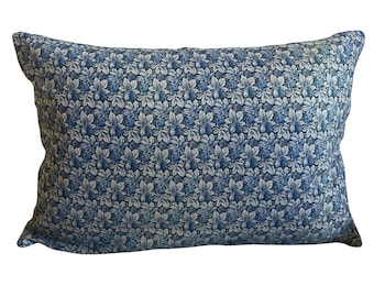 May include: Rectangular decorative pillow with a blue and white floral pattern. The pillow features a repeating design of stylized flowers in shades of blue and white against a dark blue background. The pillow is a soft, comfortable home decor item.