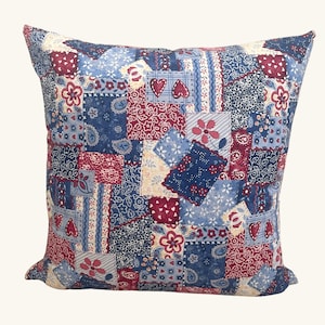 May include: A blue and red patchwork pillow with a variety of floral and paisley patterns. The pillow is made of cotton fabric and has a square shape.
