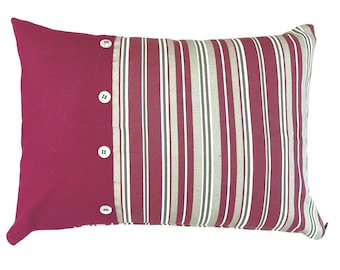 May include: A red and white striped pillow with a solid red panel and three white buttons. The pillow is made of a soft, woven fabric.