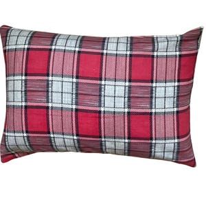 May include: Rectangular decorative pillow with a red and gray plaid pattern. The pillow features a classic tartan design with intersecting lines in red, gray, black, and white. The pillow is a home decor item.