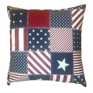 May include: A red, white, and blue patchwork pillow with a variety of American flag patterns. The pillow is made of cotton fabric and has a sewn-in look.