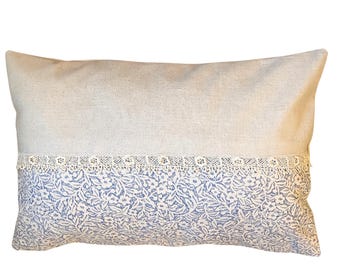 May include: A rectangular pillow with a light beige linen fabric cover. The pillow has a white lace trim and a blue floral pattern on the bottom half.
