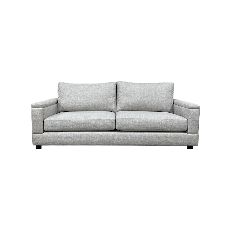 Puede incluir: Un sof&aacute; de tela gris con dos cojines y forma rectangular.