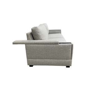 Puede incluir: Un sof&aacute; de tela gris con una mesa auxiliar incorporada y un reposabrazos negro. El sof&aacute; tiene un dise&ntilde;o moderno y es perfecto para una sala de estar o una sala familiar.