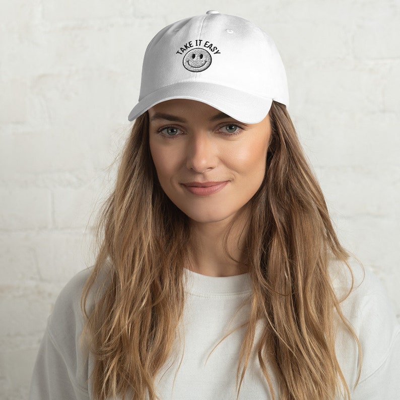 May include: White baseball cap with black embroidered text that reads "Take it Easy" and a smiley face.