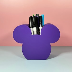 May include: Purple Mickey Mouse shaped desk organizer with black and blue markers inside.