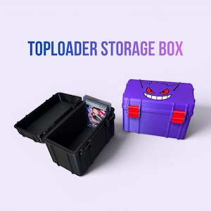 May include: Black and purple toploader storage boxes. One black box is open, revealing a stack of trading cards. A purple box features a cartoon face and red latches. The text "TOPLOADER STORAGE BOX" is displayed in the image.