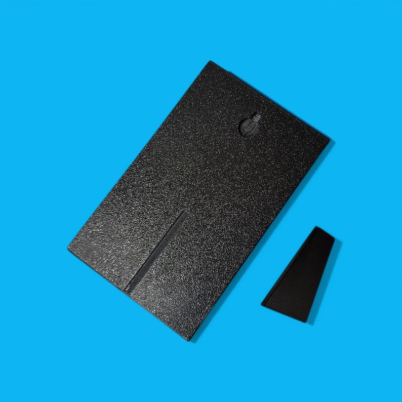 May include: A black rectangular picture frame with a textured surface and a small black stand. The frame has a slot on the back for the stand to fit into. The background is a solid blue.