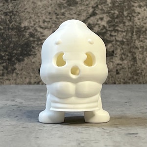 K&ouml;nnte beinhalten: Eine wei&szlig;e, 3D-gedruckte Figur eines cartoonartigen Charakters mit &uuml;berraschtem Gesichtsausdruck. Die Figur hat gro&szlig;e, ovale Augen, einen weit ge&ouml;ffneten Mund und einen muskul&ouml;sen Oberk&ouml;rper. Die Figur steht auf einer flachen Oberfl&auml;che.