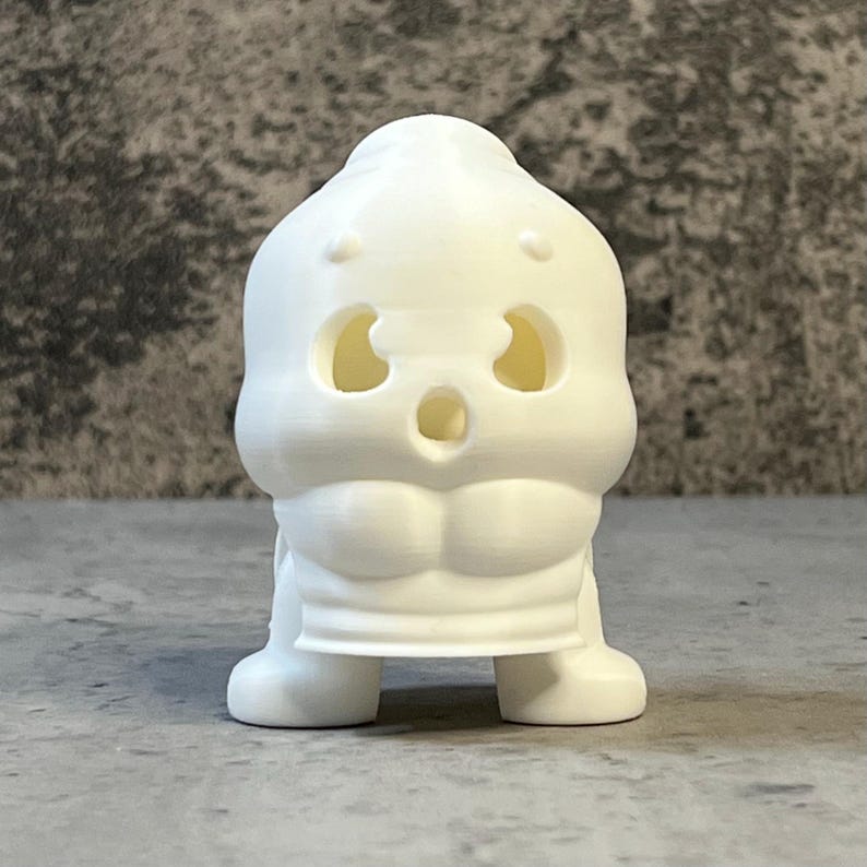 K&ouml;nnte beinhalten: Eine wei&szlig;e, 3D-gedruckte Figur eines cartoonartigen Charakters mit &uuml;berraschtem Gesichtsausdruck. Die Figur hat gro&szlig;e, ovale Augen, einen weit ge&ouml;ffneten Mund und einen muskul&ouml;sen Oberk&ouml;rper. Die Figur steht auf einer flachen Oberfl&auml;che.