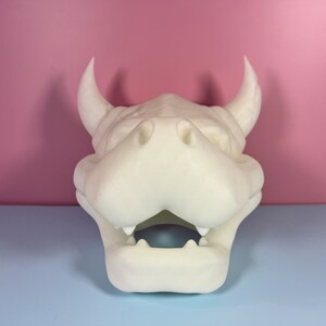 Puede incluir: Cabeza de drag&oacute;n blanca impresa en 3D con la boca abierta y dientes afilados. La cabeza est&aacute; hecha de pl&aacute;stico blanco liso.