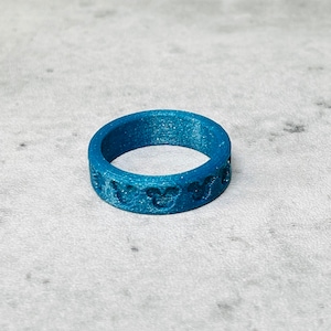 May include: A blue silicone ring with a repeating pattern of Mickey Mouse heads.