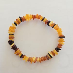 May include: An amber bracelet featuring beads in shades of yellow, orange, and brown. The beads are irregularly shaped and have a natural, polished finish.