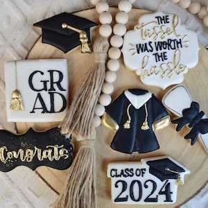 Pu&ograve; includere: Un set di biscotti di laurea decorati con glassa nera e dorata. I biscotti raffigurano un cappello di laurea, un diploma, una toga e il testo "Congrats", "Grad", "Class of 2024" e "The tassel was worth the hassle".