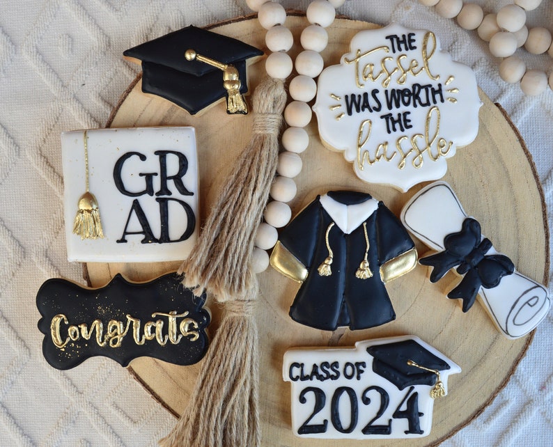 Pu&ograve; includere: Un set di biscotti di laurea decorati con glassa nera e dorata. I biscotti raffigurano un cappello di laurea, un diploma, una toga e il testo "Congrats", "Grad", "Class of 2024" e "The tassel was worth the hassle".