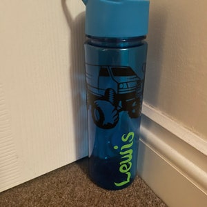 May include: A blue water bottle with a black monster truck design and the name "Lewis" in green lettering.
