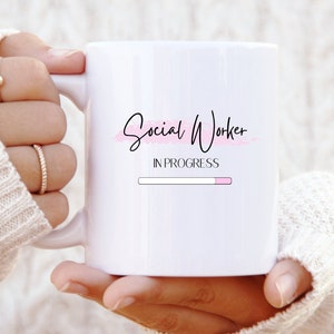 Könnte beinhalten: Eine weiße Keramiktasse mit einem rosa und schwarzen Design, auf dem "Social Worker In Progress" steht, mit einer Fortschrittsanzeige darunter.