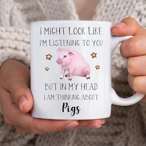 以下が含まれることがあります： ピンクの豚のイラストと「私はあなたに耳を傾けているように見えるかもしれませんが、私の頭の中では豚のことを考えています」というテキストが書かれた白いセラミックマグカップです。