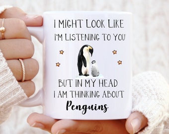 Può includere: Una tazza in ceramica bianca con un'illustrazione in bianco e nero di due pinguini. Il testo sulla tazza recita "Potrei sembrare che ti stia ascoltando, ma nella mia testa sto pensando ai pinguini."