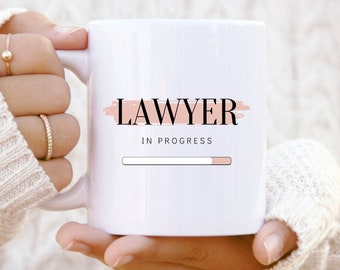 May include: White ceramic mug with the text "LAWYER IN PROGRESS" and a progress bar graphic. The progress bar is partially filled.