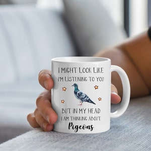 May include: White ceramic coffee mug with a black and white illustration of a pigeon and the text "I might look like I'm listening to you but in my head I am thinking about pigeons".