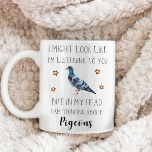 May include: White ceramic mug with a black and gray pigeon illustration and the text "I might look like I'm listening to you, but in my head I am thinking about pigeons".