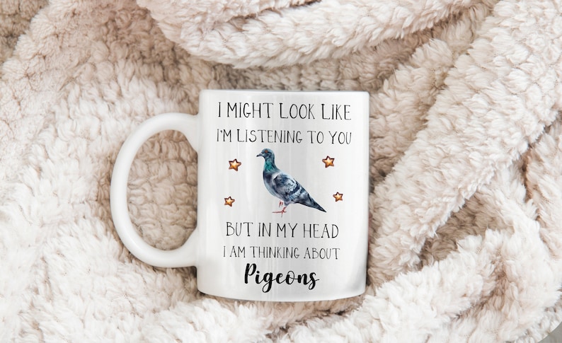 May include: White ceramic mug with a black and gray pigeon illustration and the text "I might look like I'm listening to you, but in my head I am thinking about pigeons".