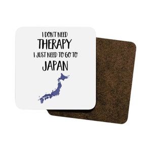 May include: White coaster with black text that reads "I don't need therapy I just need to go to Japan" with a blue outline of the country of Japan.