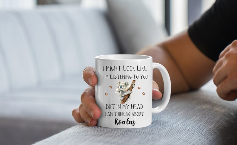 May include: White ceramic coffee mug featuring a koala illustration and the text "I might look like I'm listening to you, but in my head I am thinking about Koalas."