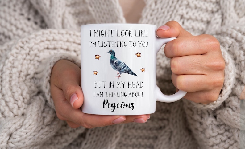 May include: White ceramic mug with a black and gray pigeon illustration and the text "I might look like I'm listening to you, but in my head I am thinking about pigeons".