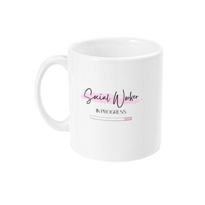 Puede incluir: Taza de cer&aacute;mica blanca con un dise&ntilde;o rosa y negro que dice "Social Worker In Progress" con una barra de progreso.