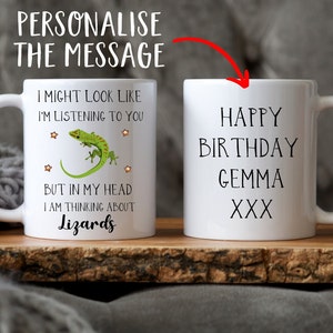 Pu&ograve; includere: Due tazze in ceramica bianca. Una tazza presenta una lucertola verde con stelle e il testo "Potrei sembrare che ti stia ascoltando, ma nella mia testa sto pensando ai rettili". L'altra tazza ha il testo "Buon compleanno Gemma XXX".
