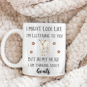 May include: White ceramic coffee mug with a black and white goat illustration and the text "I might look like I'm listening to you but in my head I am thinking about Goats".