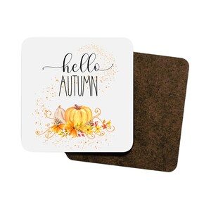 Puede incluir: Posavasos cuadrado con una superficie blanca con el texto "hello AUTUMN" en escritura negra. El dise&ntilde;o incluye calabazas de acuarela, hojas y detalles florales en tonos naranja, amarillo y blanco. El segundo posavasos es marr&oacute;n.
