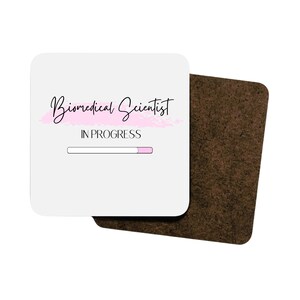 May include: White coaster with a pink brushstroke and the text "Biomedical Scientist" in black cursive font. Below the text is a progress bar with the text "IN PROGRESS" in black.