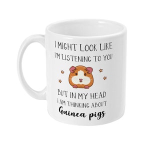 May include: White ceramic mug with a black and white illustration of a guinea pig and the text "I might look like I'm listening to you but in my head I am thinking about Guinea pigs".