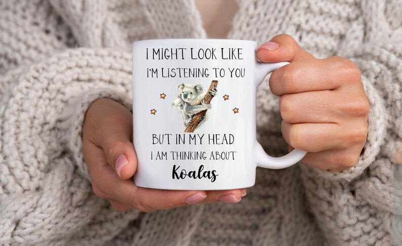May include: White ceramic mug with a black and white illustration of a koala and the text "I might look like I'm listening to you but in my head I am thinking about Koalas".