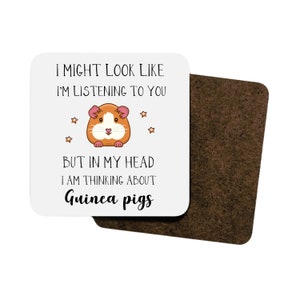 May include: White coaster featuring a cartoon guinea pig and the text "I might look like I'm listening to you, but in my head I am thinking about guinea pigs."