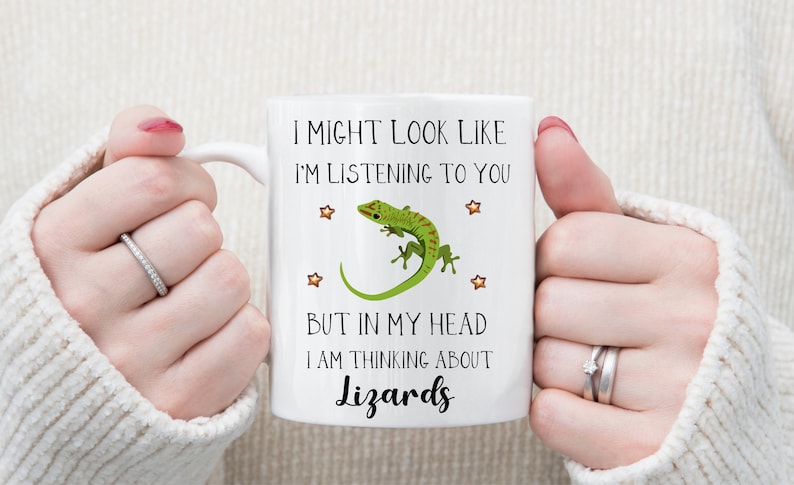 Pu&ograve; includere: Una tazza in ceramica bianca con un grafico di lucertola verde e il testo "Potrei sembrare che ti stia ascoltando, ma nella mia testa sto pensando ai rettili".