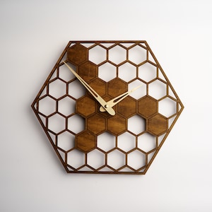 May include: A hexagonal wooden wall clock with gold-coloured hands. The clock face is made of a honeycomb pattern.