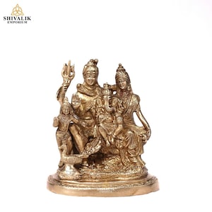 May include: A gold-coloured brass statue of the Hindu deities Shiva, Parvati, and Ganesha. Shiva is holding a trident and sitting with his leg crossed. Parvati is sitting next to him with her hand on his shoulder. Ganesha is sitting on Shiva's lap. The statue is on a round base.