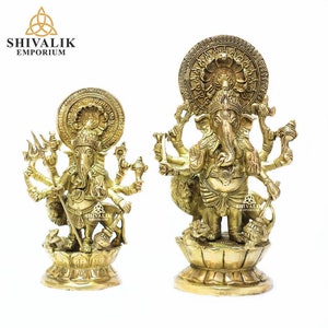 Könnte beinhalten: Zwei goldfarbene Messingstatuen von Ganesha, dem hinduistischen Gott der Weisheit und des Wohlstands. Beide Statuen stehen auf Lotussockeln und haben mehrere Arme, die verschiedene Gegenstände halten. Die Statue links hält in einer Hand einen Dreizack, während die Statue rechts in einer Hand einen kleinen Elefanten hält. Beide Statuen haben einen Heiligenschein hinter dem Kopf.