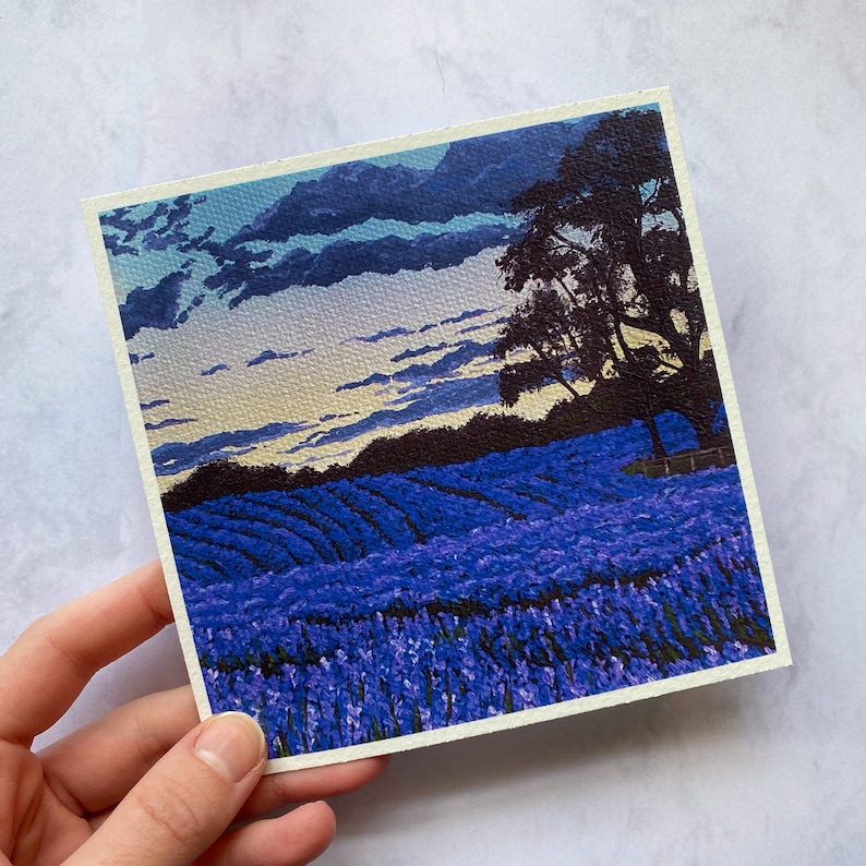 May include: A painting of a field of purple flowers with a silhouette of a tree in the background. The sky is a light blue with white clouds.