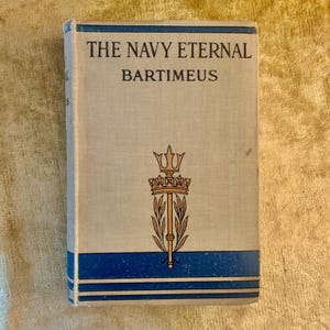 May include: A vintage book titled "The Navy Eternal" by Bartimeus. The book has a light-colored cover with blue accents and gold and brown illustrations. The cover features a crown and leaf design.