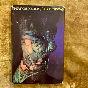 May include: A book cover with a photo of a person in a jungle setting. The book title is "The Virgin Soldiers" by Leslie Thomas.