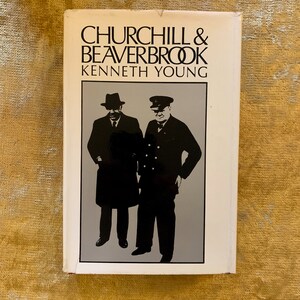 May include: A white book cover with black text that reads "Churchill & Beaverbrook Kenneth Young". The cover features a black and white silhouette of two men in suits and hats.