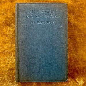 May include: A blue hardcover book with the title "An Awfully Big Adventure" by "Bartimeus" printed on the front cover.