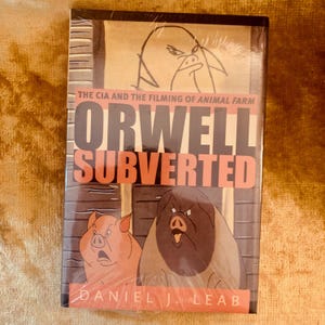 May include: A book titled "Orwell Subverted" by Daniel J. Leab, sealed in clear plastic. The cover displays illustrations of pigs and a bird, with the text "The CIA and the Filming of Animal Farm".